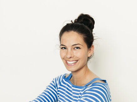 Schöne junge Frau mit schwarzen Haaren und blau-weiß gestreiften Pullover ist vor dem weißen Hintergrund posiert - HMEF00426
