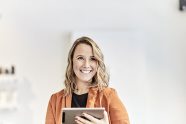 Portrait of smiling young businesswoman with mini tablet - FMKF05679