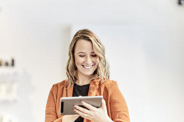 Portrait of smiling young businesswoman using mini tablet - FMKF05680