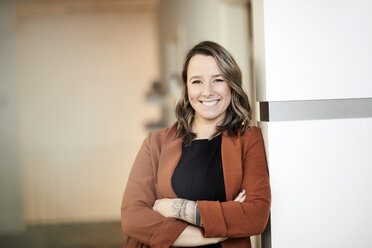 Portrait of smiling young businesswoman with tattoo - FMKF05693