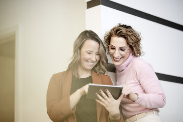 Two businesswomen looking at mini tablet having fun - FMKF05695
