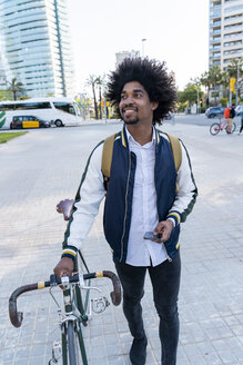 Casual businessman with bicycle and cell phone in the city on the go, Barcelona, Spain - AFVF03030