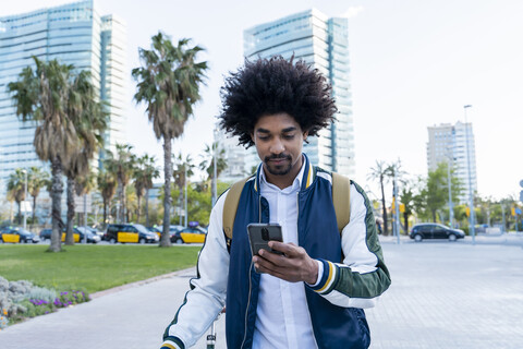 Casual businessman with bicycle using cell phone in the city, Barcelona, Spain stock photo