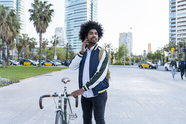 Casual businessman with bicycle on cell phone in the city, Barcelona, Spain - AFVF03032