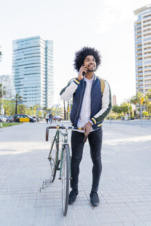 Lässiger Geschäftsmann mit Fahrrad auf Handy in der Stadt, Barcelona, Spanien - AFVF03035