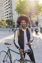 Porträt eines lächelnden Geschäftsmannes mit Fahrrad und Mobiltelefon in der Stadt, Barcelona, Spanien - AFVF03037