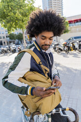 Lässiger Geschäftsmann mit Fahrrad und Handy in der Stadt, Barcelona, Spanien - AFVF03040