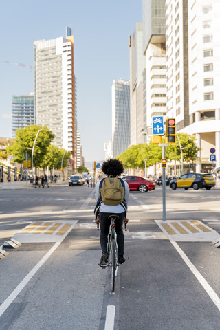 Rear view of casual businessman on bicycle in the city, Barcelona, Spain stock photo