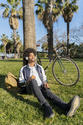 Casual businessman taking a break in urban park listening to music, Barcelona, Spain - AFVF03061