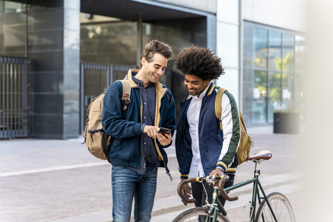 Zwei glückliche Geschäftsleute mit Mobiltelefonen treffen sich in der Stadt, Barcelona, Spanien, lizenzfreies Stockfoto