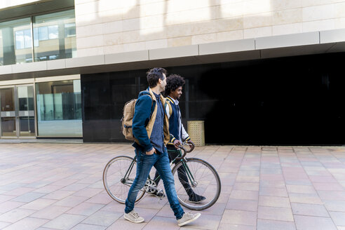 Zwei lässige Geschäftsleute mit Fahrrad beim Spaziergang in der Stadt, Barcelona, Spanien - AFVF03080