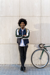 Portrait of smiling casual businessman with bicycle standing at a wall - AFVF03130