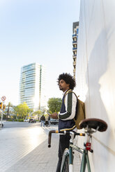 Lässiger Geschäftsmann mit Fahrrad und Mobiltelefon in der Stadt, Barcelona, Spanien - AFVF03135