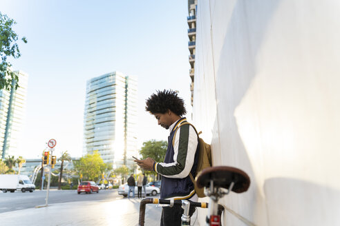 Lässiger Geschäftsmann mit Fahrrad und Handy in der Stadt, Barcelona, Spanien - AFVF03136