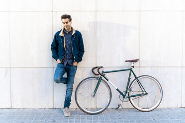 Porträt eines lässigen Mannes mit Fahrrad, der an einer Wand steht - AFVF03138