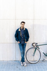 Portrait of casual man with bicycle standing at a wall - AFVF03139