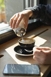 Woman's hand pouring sugar into cup of coffee - FBAF00631