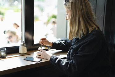 Junge Frau entspannt sich in einem Kaffeehaus - FBAF00632