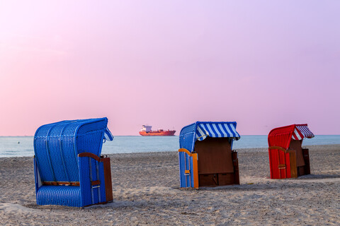 Drei Strandkörbe mit Kapuze bei Sonnenuntergang, Warnemünde, Rostock, Deutschland, lizenzfreies Stockfoto