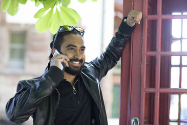 Portrait of smiling young man on the phone outdoors - SGF02374