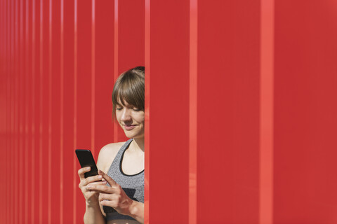 Sportlerin, die vor einer roten Wand telefoniert, lizenzfreies Stockfoto