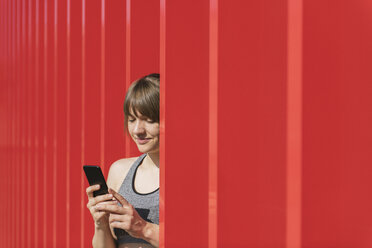 Sportlerin, die vor einer roten Wand telefoniert - AHSF00450