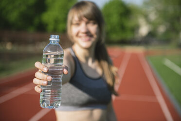 Sportlerin bietet eine Flasche Wasser an - AHSF00470