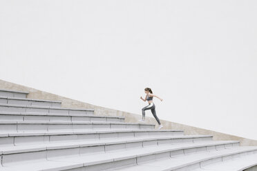 Young woman running on concrete bleachers - AHSF00478