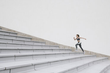 Young woman running on concrete bleachers - AHSF00479