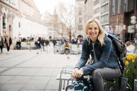 Porträt einer lächelnden blonden Frau mit Gepäck in der Stadt, München, Deutschland, lizenzfreies Stockfoto