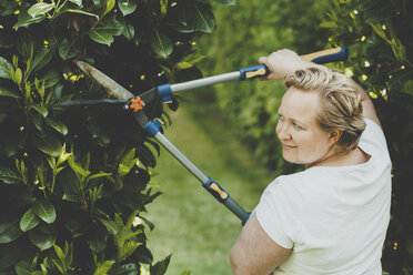 Eine Frau schneidet die Sträucher mit einer großen Gartenschere - IHF00072