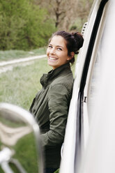 Laughing young woman leaning on camper - HMEF00450