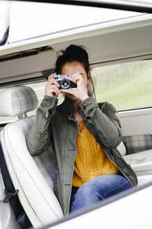 Junge Frau sitzt im Wohnmobil und macht Fotos - HMEF00452