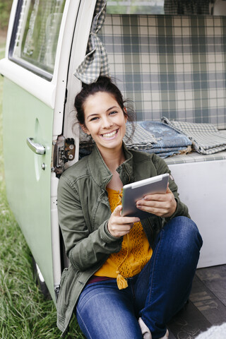 Junge Frau mit digitalem Tablet, sitzend in ihrem Wohnmobil, lizenzfreies Stockfoto