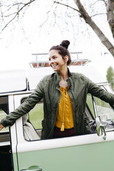 Laughing young woman leaning aout of wondow of her camper - HMEF00457