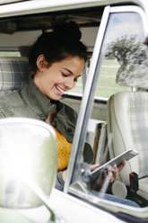 Junge Frau mit digitalem Tablet, sitzend in ihrem Wohnmobil - HMEF00460