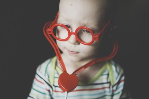 Portrait of toddler boy wearing oversized red toy glasses and toy stethoscope stock photo