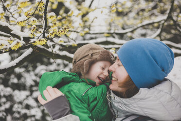 Mutter mit ihrem kleinen Sohn unter einer Schneedecke unter einem Hexenhaselbaum - IHF00079
