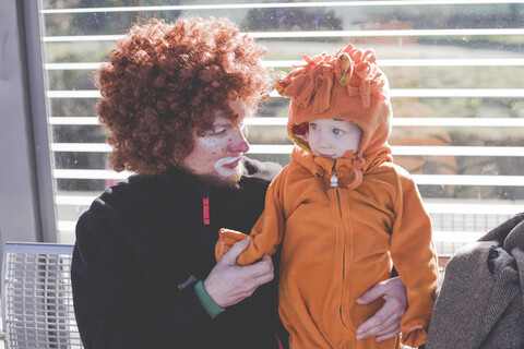 Ein als Clown verkleideter Mann und ein als Löwenbaby verkleideter kleiner Junge beim Karneval, lizenzfreies Stockfoto