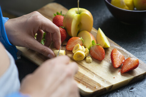 Frau schneidet Früchte in ihrer Küche, Nahaufnahme, lizenzfreies Stockfoto