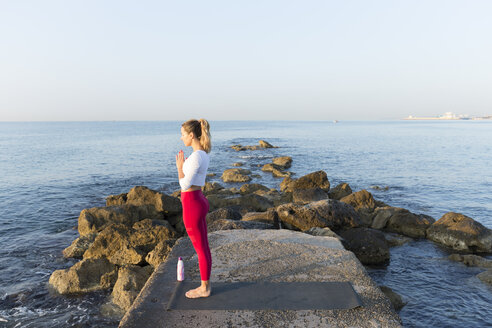 Young woman practicing yoga on the beach, doing prayer position - JPTF00088