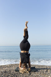 Junge Frau übt Yoga am Strand, macht Kopfstand - JPTF00126