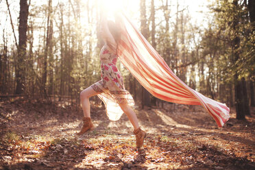 Hispanic woman running with scarf in forest - BLEF05788