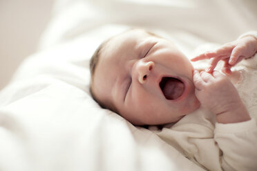 Kaukasisches Babymädchen gähnt auf dem Bett - BLEF05803