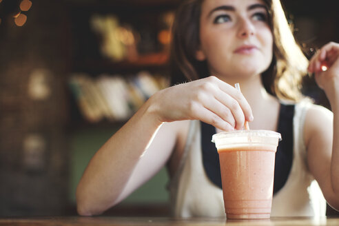 Kaukasisches Teenager-Mädchen trinkt Smoothie im Cafe - BLEF05806