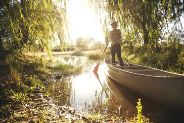 Caucasian woman rowing canoe in rural creek - BLEF05810