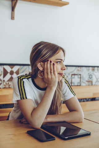 Junge Frau sitzt in einem Café und schaut weg, lizenzfreies Stockfoto