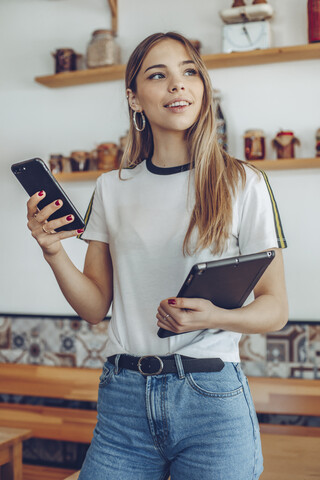 Porträt einer jungen Frau, die ein Tablet in einem Café hält, lizenzfreies Stockfoto