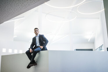 Businessman sitting on reception desk in office - MOEF02178