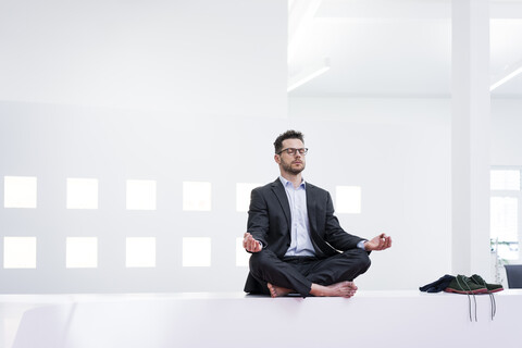 Businessman doing yoga in office stock photo